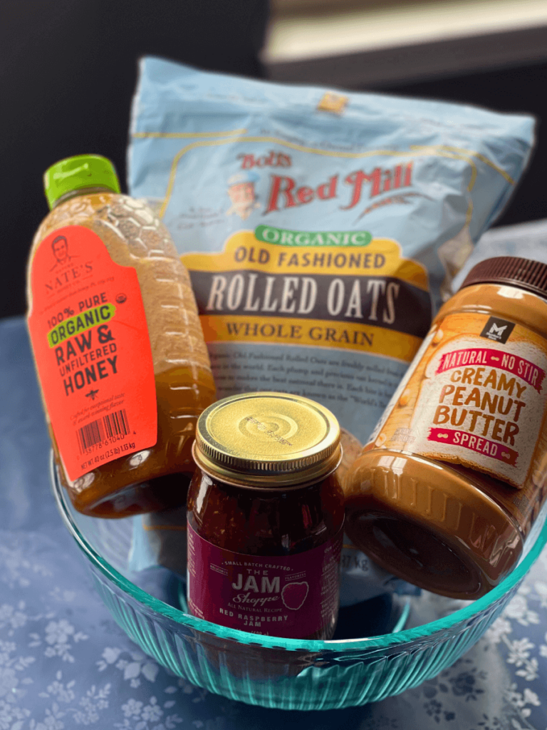 ingredients for no bake peanut butter and jelly bars in a glass bowl - old fashioned rolled oats, honey, jam and peanut butter