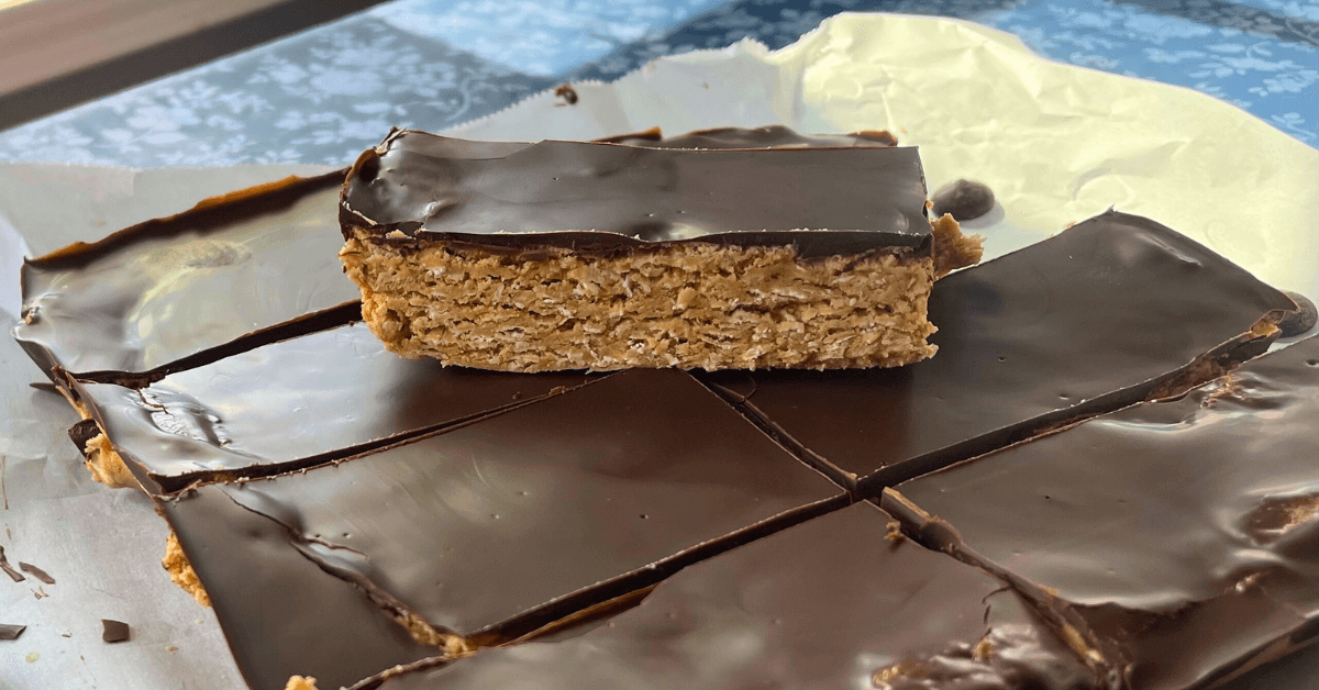 up close shot of a cut peanut butter and dark chocolate oat bar on parchment paper with one on top of the others exposing the layers
