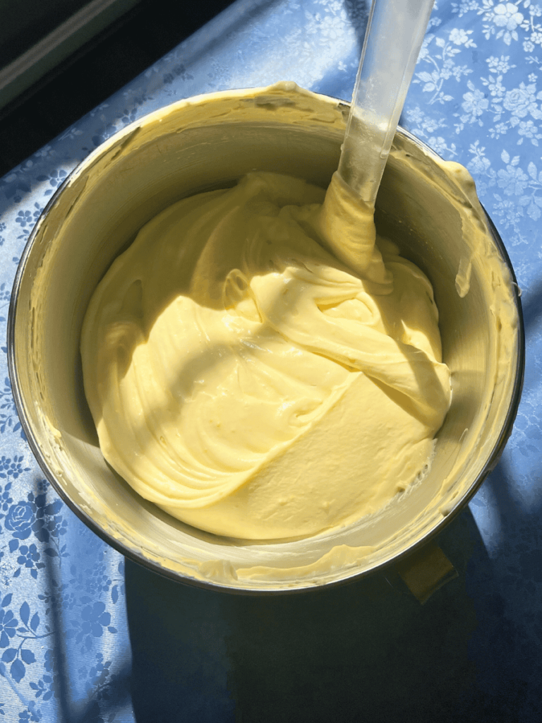 bowl of french vanilla pudding and homemade whipped cream mixed together in a large bowl set on a table with a blue floral table cloth