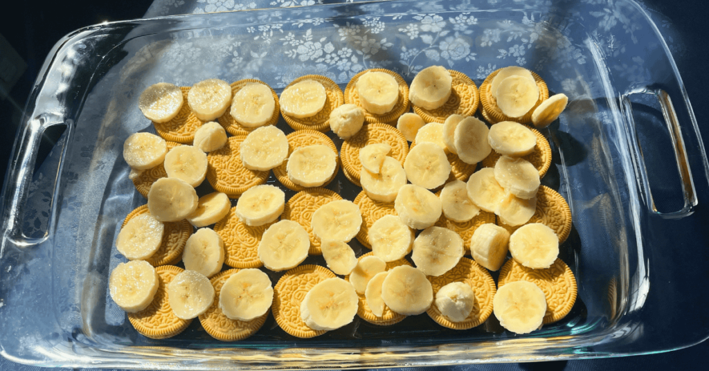 Golden Oreos and banana slices layering the bottom of a 13x9 glass pan