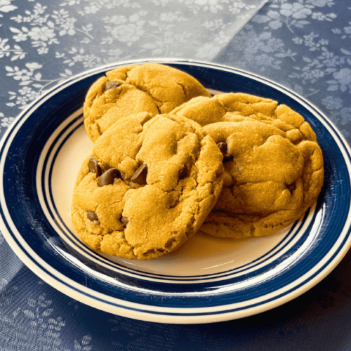 three soft peanut butter chocolate chip cookies on a small white and navy plate