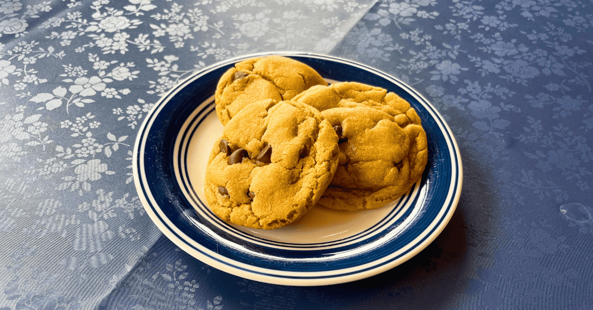 three soft peanut butter chocolate chip cookies on a small white and navy plate