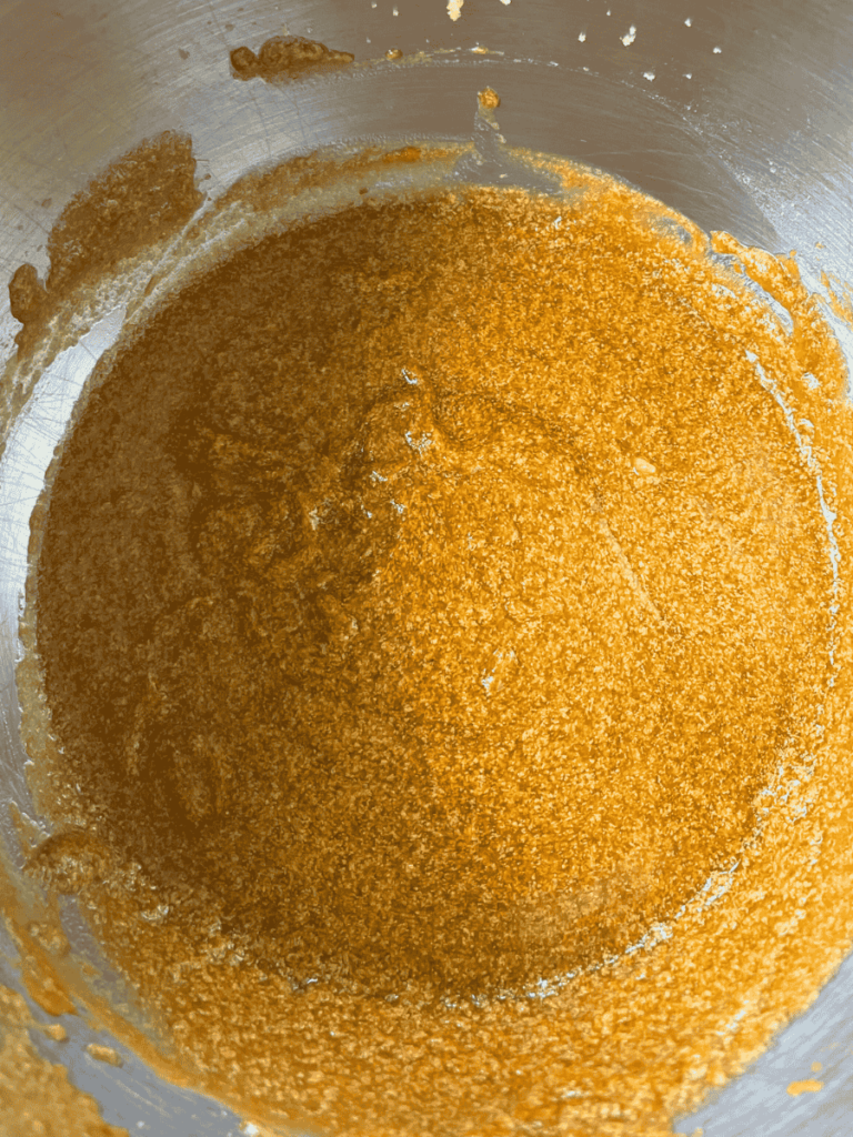 overhead shot of wet ingredients for oatmeal pumpkin chocolate chip cookies blended together in a stainless steel mixing bowl