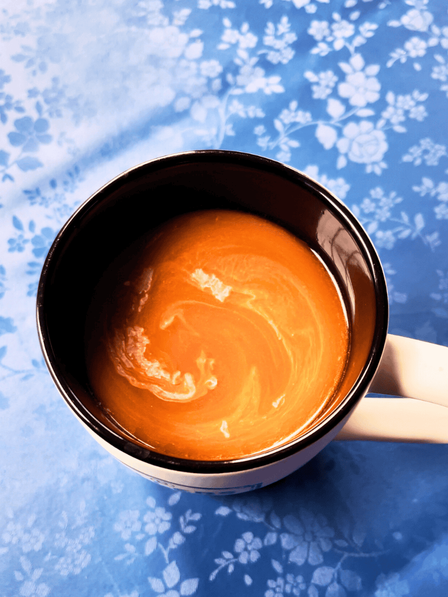 overhead shot of a cup of coffee sitting on a table with a blue floral table cloth