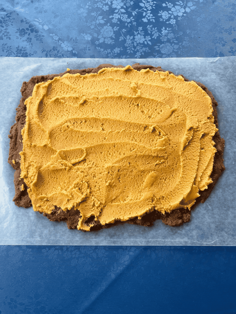 dark chocolate brownie cookie dough base spread into a 13"x10" rectangle on wax paper and topped with peanut butter filling