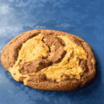 side shot of peanut butter brownie swirl cookie sitting on a blue floral table cloth