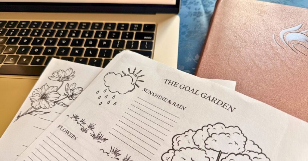 printed copy of the goal garden monthly goal setting template sitting on top of an opened laptop and closed brown faux leather planner