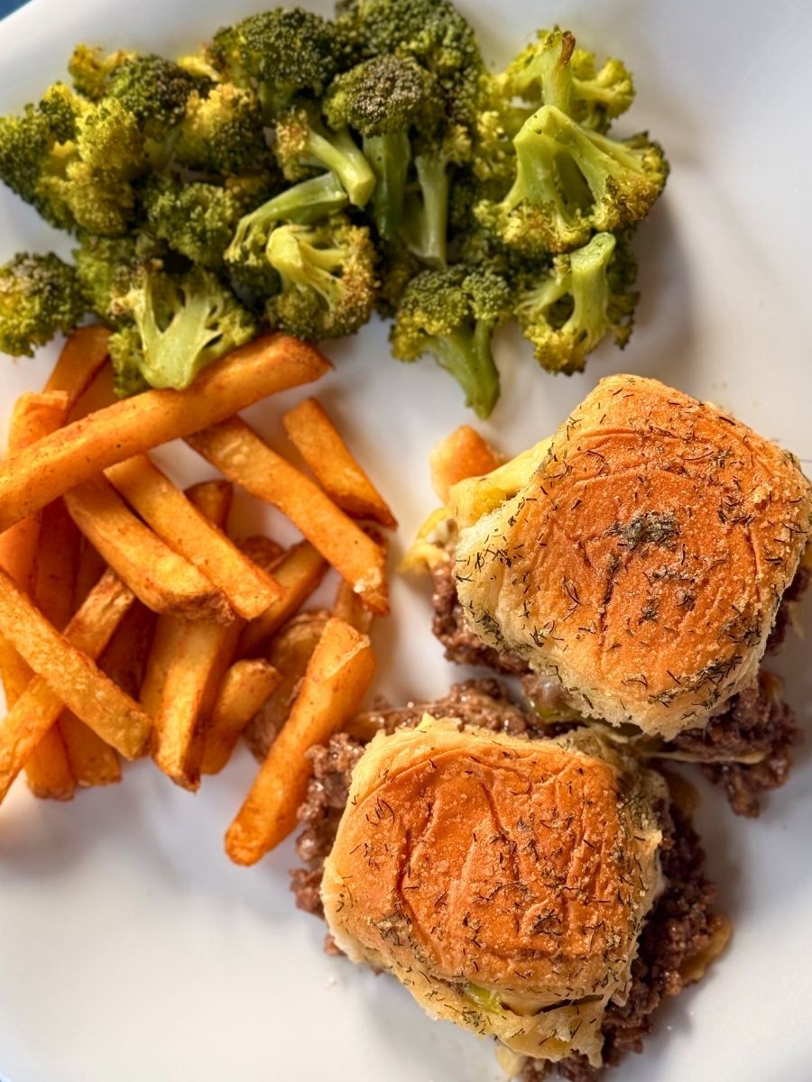 mississippi sliders served on a white dinner plate with french fries and roasted broccoli