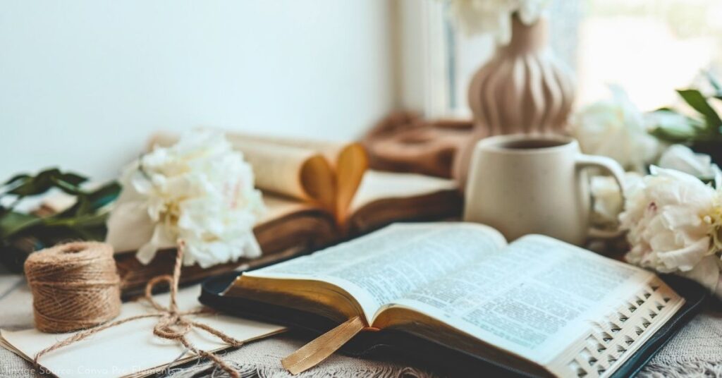 open bible laying on a table with coffee cup and flowers
