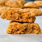 a peanut butter oatmeal cookie with butterscotch chips broke in half with one half stacked on the other exposing the inside of the cookie